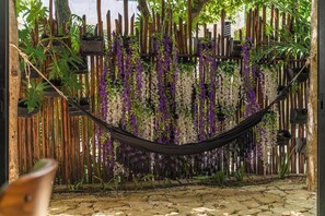 A hammock suspended over a wooden fence with hanging plants and a stone pathway. - Casa Natura, Private Plunge w Bikes (Tulum)