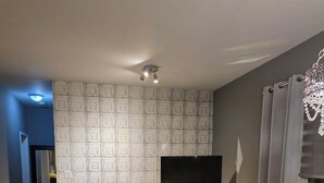 Una sala de estar moderna con un sofá gris, un tapete estampado, un sillón de cuero negro, una mesita y un televisor.
