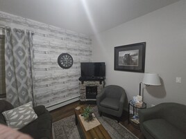 Una sala de estar con chimenea, televisor y un cuadro en la pared.