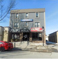 Un edificio con un letrero que dice 'Executive Suites' y un restaurante de pizza llamado '24 Pizza' en la calle King.