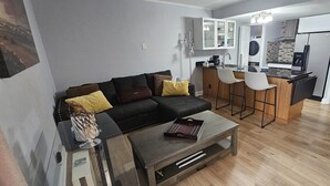 Una sala de estar moderna con sofá, mesa de centro y área de cocina con barra y sillas.