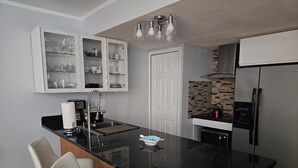 Una cocina moderna con cubierta negra, armarios blancos y microondas integrado.