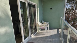 Un balcón con puerta corredera de vidrio, una mesita y una silla.