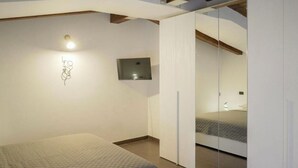 A bedroom with a bed, a wall-mounted light, a flat-screen TV, and a sliding closet door. - Casa Soele your home away from home (Pontecagnano)