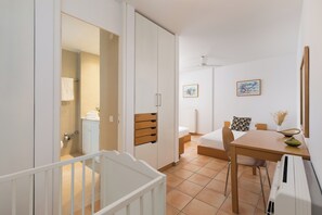Un dormitori modern amb llit, taula de nit i una petita zona d'estar amb una cadira i taula.