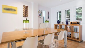 A dining area with a wooden table, white chairs, and a shelf with decorative items. - Villa Piedra, Seafront 3 Bedroom Villa with Direct Beach Access - Barbati, Corfu (Mparmpati)