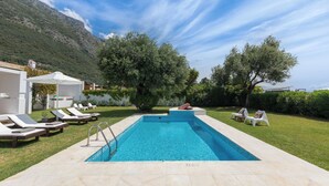 A rectangular swimming pool with a clear blue water, surrounded by a well-maintained lawn and lounge chairs. - Villa Piedra, Seafront 3 Bedroom Villa with Direct Beach Access - Barbati, Corfu (Mparmpati)