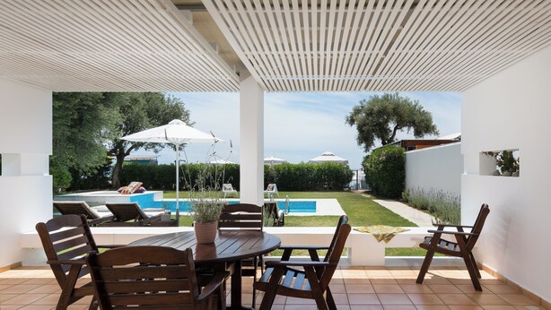 A patio with a round table and chairs, a pool, and a view of the garden. - Villa Piedra, Seafront 3 Bedroom Villa with Direct Beach Access - Barbati, Corfu (Mparmpati)