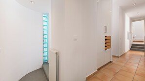 A modern hallway with white walls, a radiator, and a wooden bench. - Villa Piedra, Seafront 3 Bedroom Villa with Direct Beach Access - Barbati, Corfu (Mparmpati)