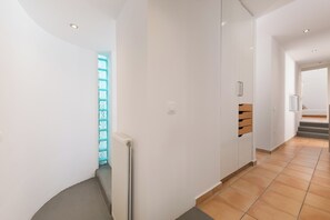 Ein moderner Flur mit weißen Wänden, einem Heizkörper und einer hölzernen Sitzbank.