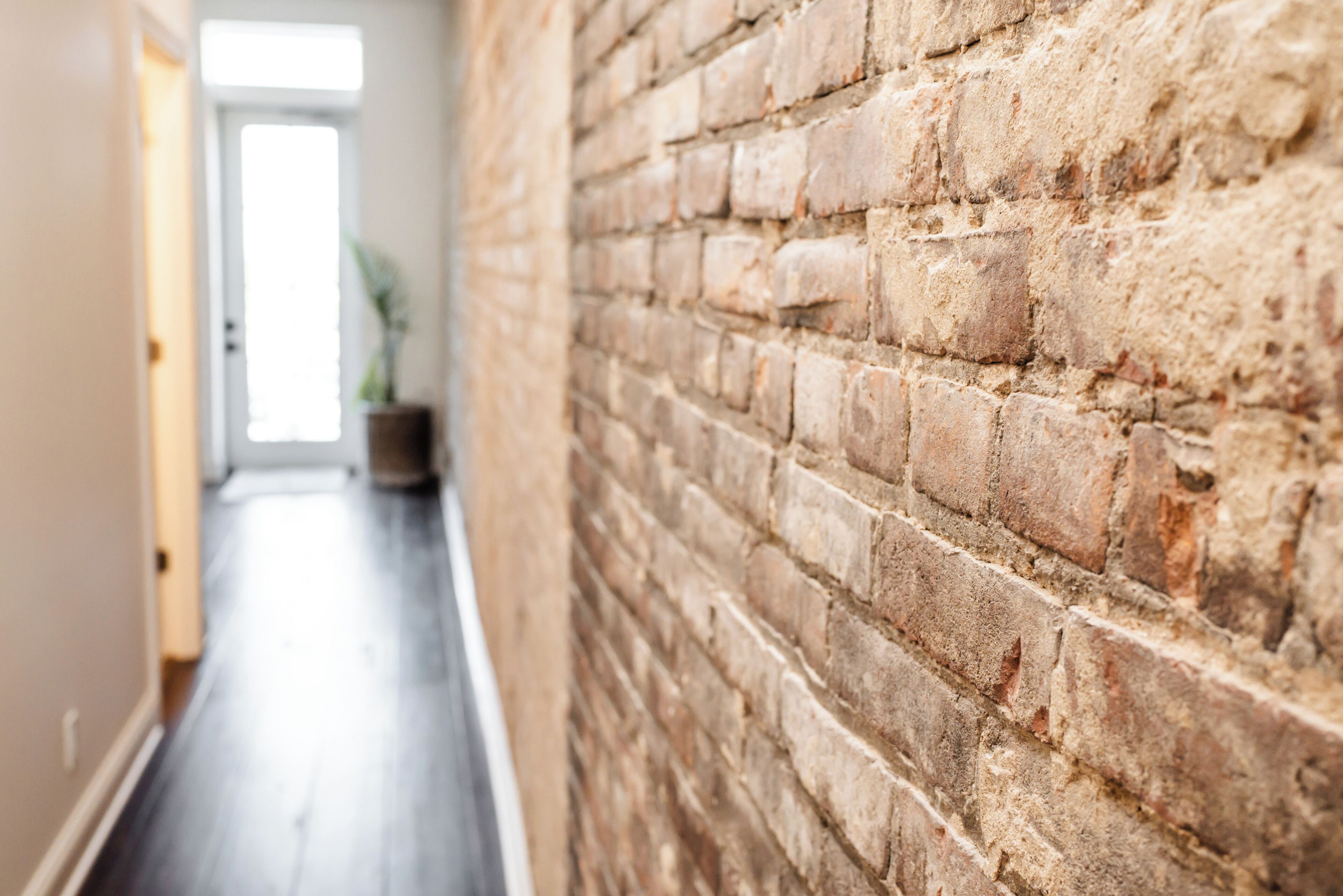 A hallway with a brick wall and wooden flooring.