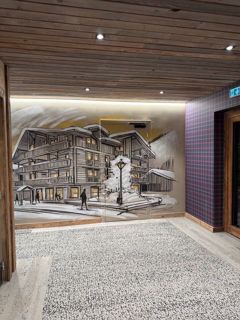 Un couloir doté d’un sol texturé et orné d’une fresque représentant un immeuble avec des balcons et des personnes.