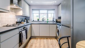 Een moderne keuken met een inbouwoven, een wasmachine en een groot raam dat voor natuurlijk licht zorgt.