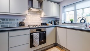 Een moderne keuken met witte kasten, een zwart aanrecht, een inbouwoven en een raam met uitzicht.