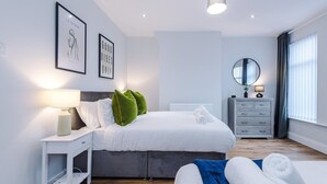 Een moderne slaapkamer met een bed, nachtkastje en een dressoir.