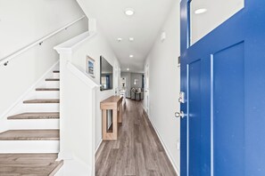 A hallway with a wooden staircase, a blue door, and a bench. - Birdie Beach House (By Beach Star) (Surfside Beach)