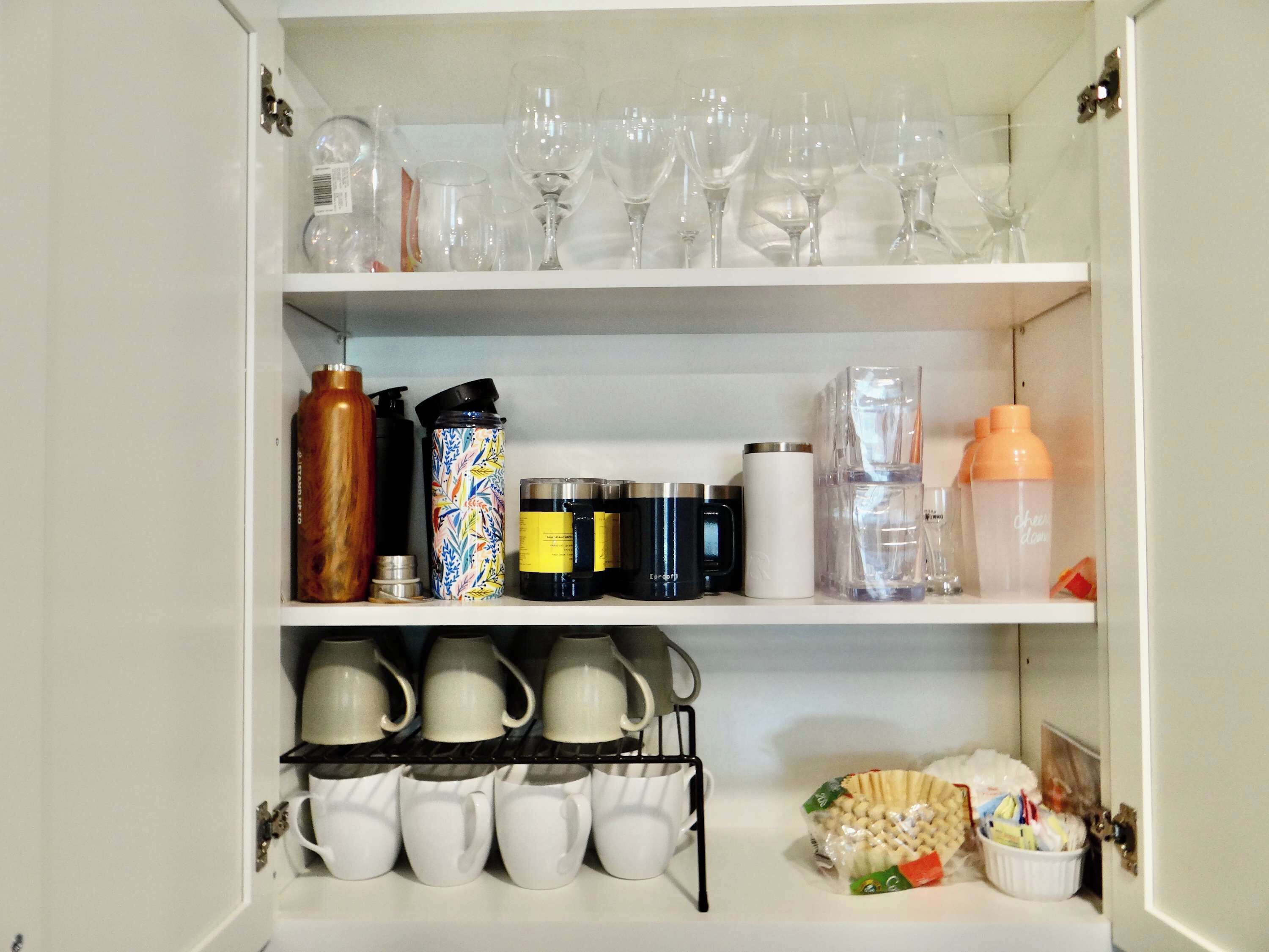 Ein Küchenschrank mit Regalen, gefüllt mit verschiedenen Küchengeräten und Utensilien.