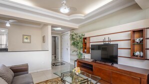 A living room with a sofa, glass coffee table, wooden entertainment unit, and a television. - Apts Just 210m From the Beach in Balneario Camboriu - Edis (Balneário Camboriú)