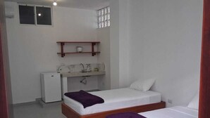 Una habitación pequeña y limpia con dos camas de madera, una kitchenette y una ventana.