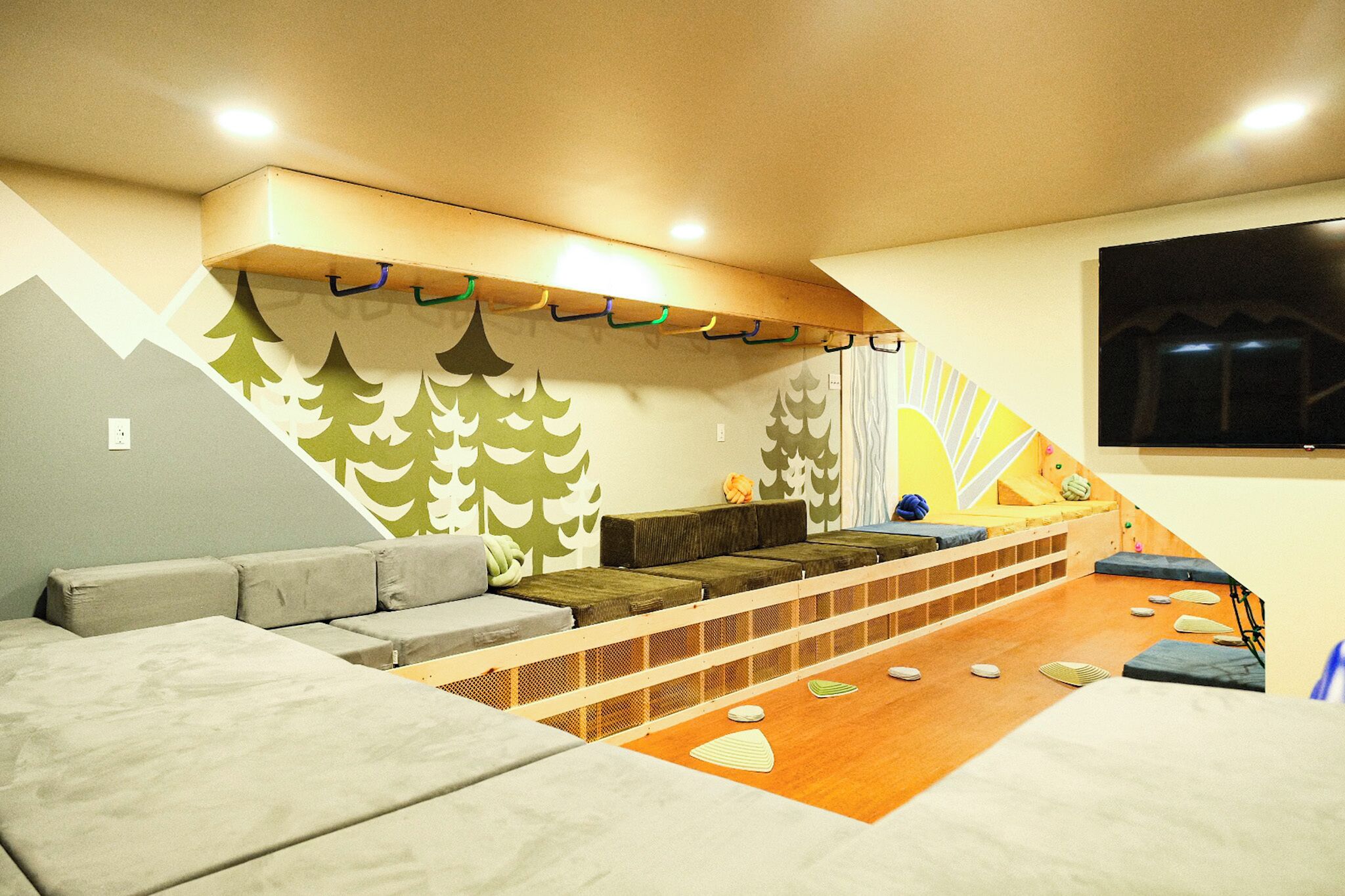 Una habitación acogedora con sofá, una plataforma de madera y televisor en la pared.