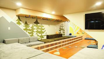 Una habitación acogedora con sofá, una plataforma de madera y televisor en la pared.