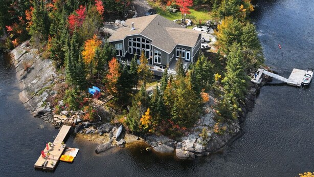 A lakeside cabin with a dock, surrounded by autumn foliage.