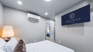 Una habitación de hotel con cama, lámpara, espejo y un letrero en la pared.