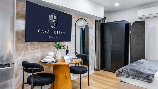 Ein modernes Hotelzimmer mit Essbereich, einem Bett und einem Kleiderschrank.