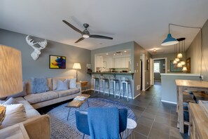 A modern living room with a sofa, coffee table, and a dining area with a table and chairs.