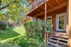 A wooden building with a covered porch, a well-maintained lawn, and a dense hedge.