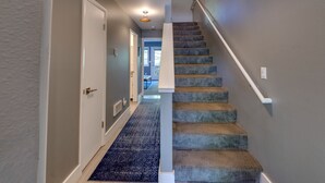 Un pasillo con una escalera alfombrada que lleva a una puerta.