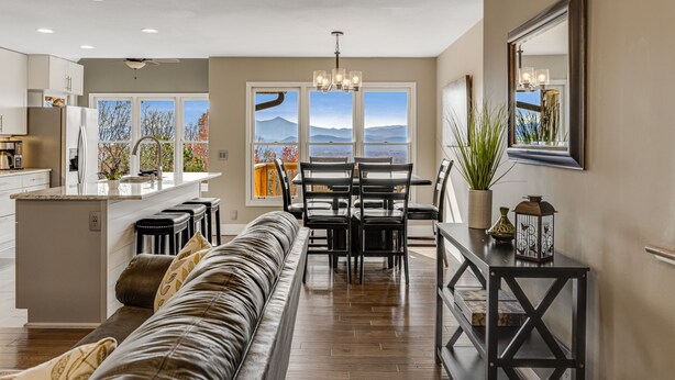 A modern kitchen with a dining area, a large window with a mountain view, and a cozy seating area with a sofa and a coffee table. - Blue Ridge Cabin w/ Gorgeous Mountain Views! (Candler)