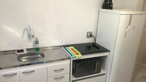 A compact kitchenette with a sink, a microwave, and a small refrigerator. - Pousada Caravela (Penha)