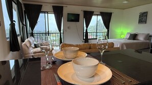 Et moderne hotelværelse med spiseplads, en sofa, en seng og en balkon med udsigt.