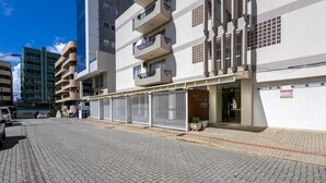 A multi-story building with a gated entrance, a sign prohibiting parking, and a paved sidewalk. - Apt in Center of Itapema 200m From the sea Ebm0122 (Itapema)