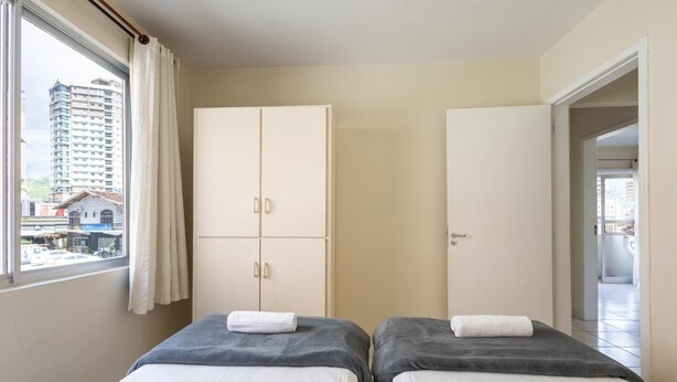 A hotel room with two beds, a wardrobe, and a view of a cityscape. - Apt in Center of Itapema 200m From the sea Ebm0122 (Itapema)