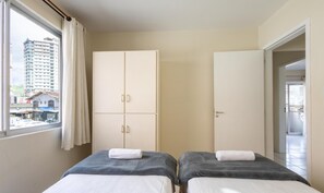 A hotel room with two beds, a wardrobe, and a view of a cityscape. - Apt in Center of Itapema 200m From the sea Ebm0122 (Itapema)