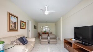 A living room with a sofa, TV, and dining area. - Apt in Center of Itapema 200m From the sea Ebm0122 (Itapema)