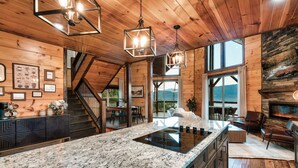 A spacious kitchen with a large island, wooden ceiling, and a stone fireplace. - Smoky Mountain Cabin w/ Incredible View- Perfect for Families-Indoor Heated Pool (Sevierville)