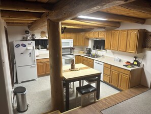 Une cuisine avec des meubles de rangement en bois, un réfrigérateur blanc, un four à micro-ondes et un évier.