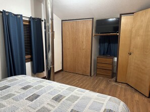 Une chambre à coucher comprenant un lit, une armoire en bois, une commode et un miroir.