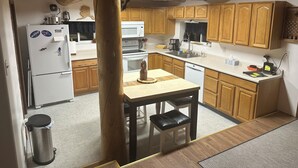 Une cuisine avec des meubles de rangement en bois, un réfrigérateur blanc, un four à micro-ondes, une cuisinière et un évier.