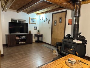 Un salon comprenant un téléviseur, un meuble de rangement en bois, une cheminée et une porte agrémentée d’éléments décoratifs.