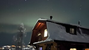 Une cabane en bois recouverte de neige, avec une fenêtre visible et une véranda.