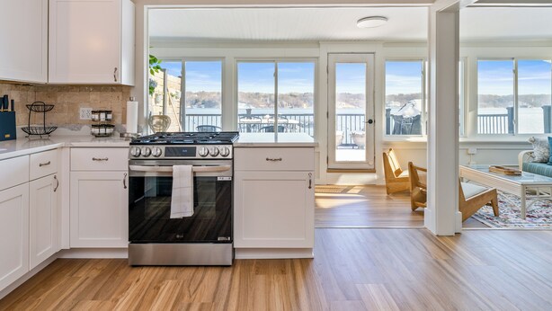 Una cocina moderna con armarios blancos, una estufa de acero inoxidable y un ventanal con vistas panorámicas.