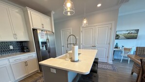 A modern kitchen with white cabinets, a central island, and a dining area with a table and chairs.