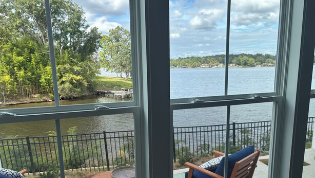 A balcony with outdoor seating and a view of a lake and trees.