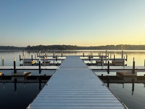 A wooden pier extending into calm water with a clear sky above.