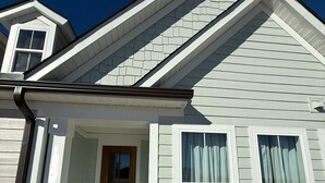 A single-story house with a front porch, a wooden door, and a visible air conditioning unit.
