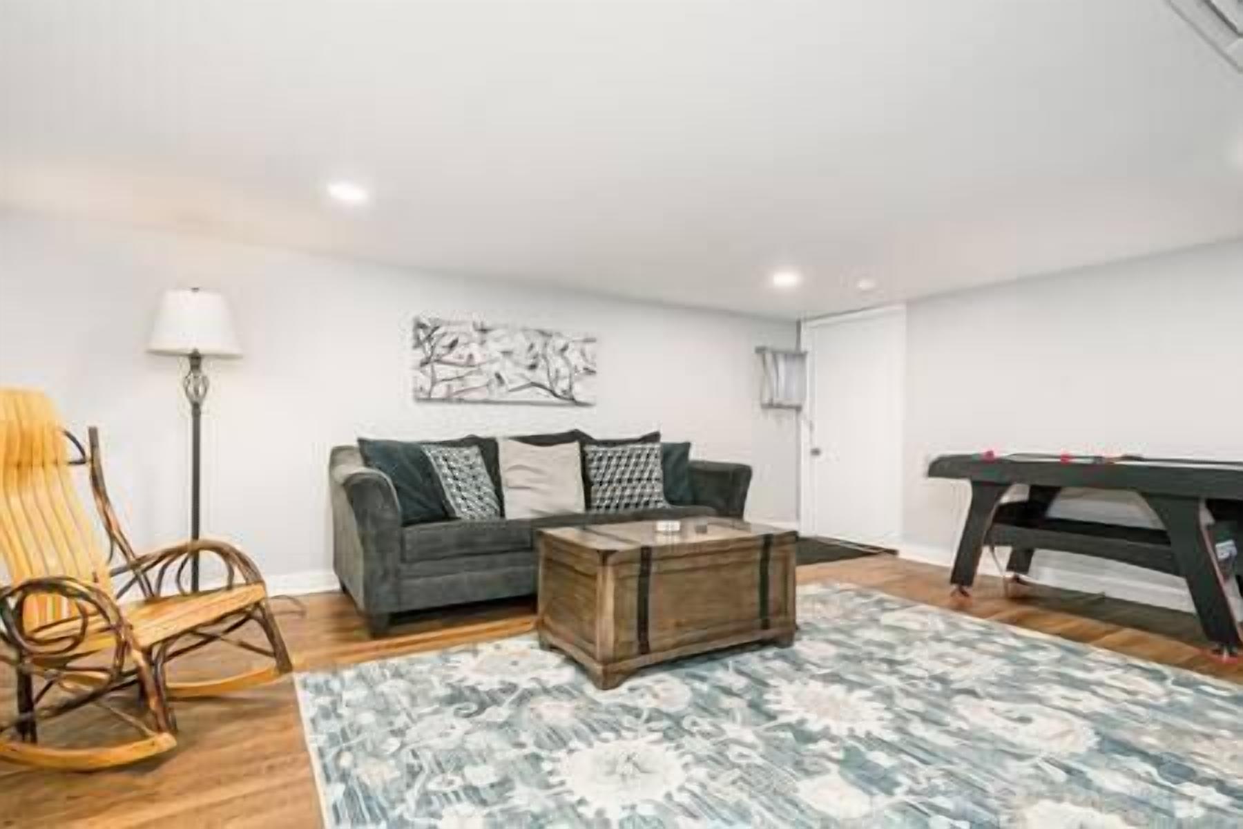 A living room with a sofa, a coffee table, a lamp, and a pool table.